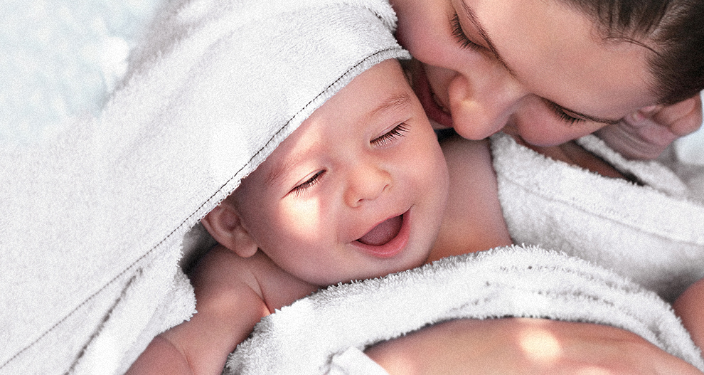 En person håller i en baby som är inlindad i en vit handduk.