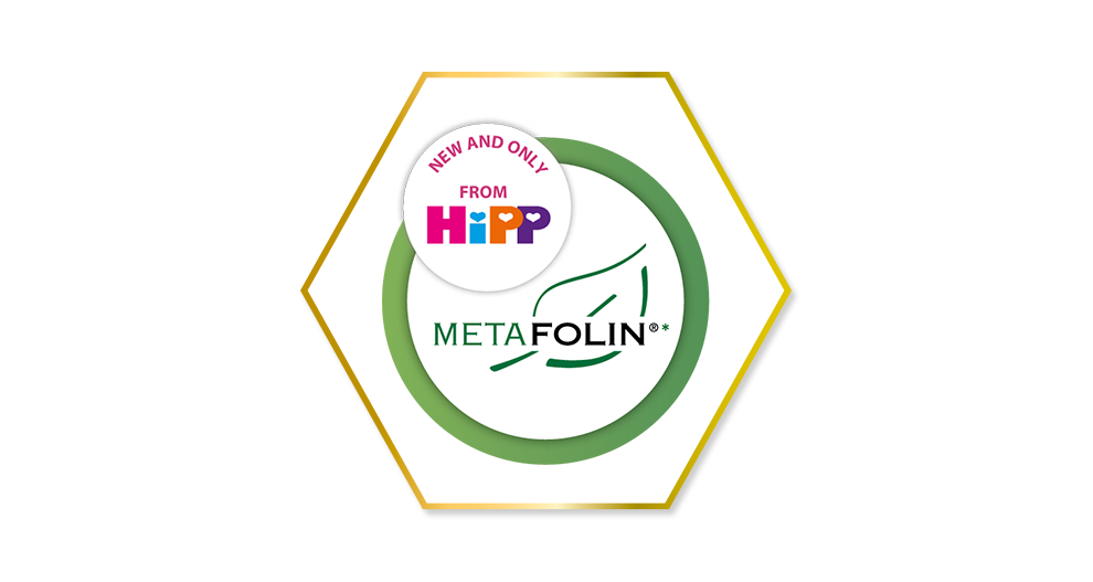 En stiliserad sexkantig form med en grön bladdesign, en cirkulär etikett med texten "NEW AND ONLY FROM HiPP" och texten "METAFOLIN" i mitten.