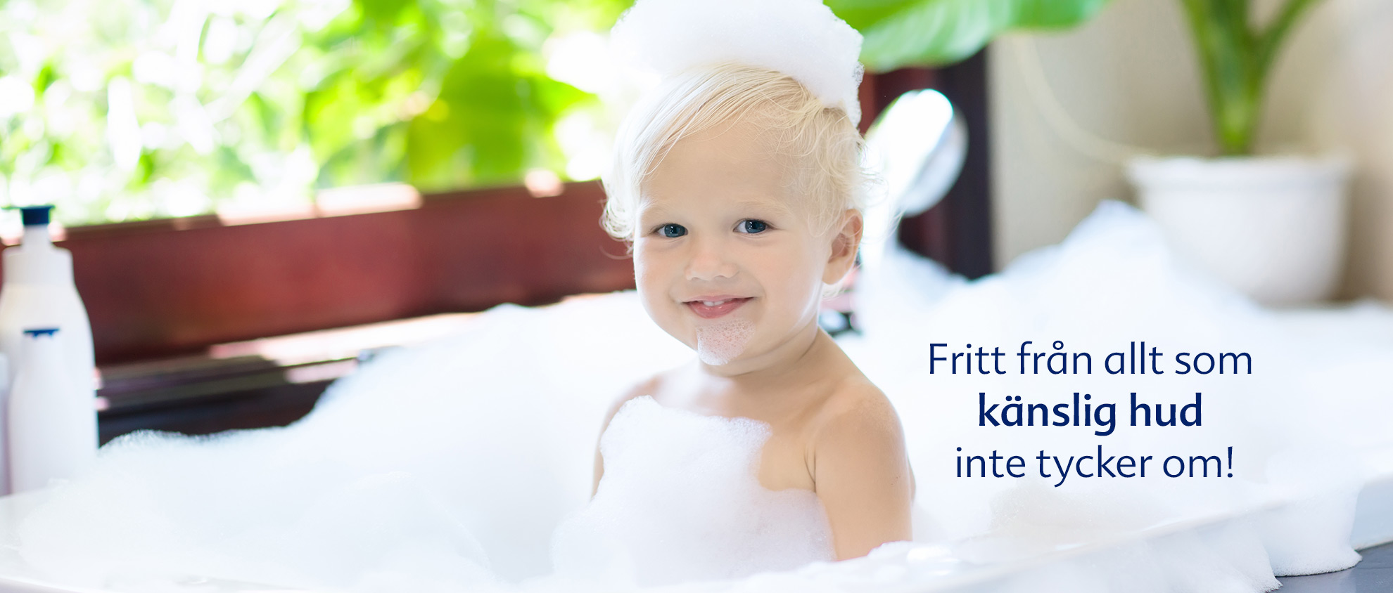 Ett litet barn tar ett bubbelbad med ett fönster i bakgrunden.